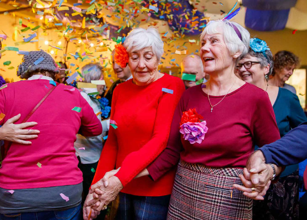 Older adults happily dancing as confetti rains down, creating a joyful atmosphere.