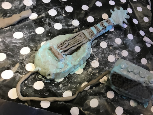 on a spotted tablecloth sits a small sculpture of a guitar and amp