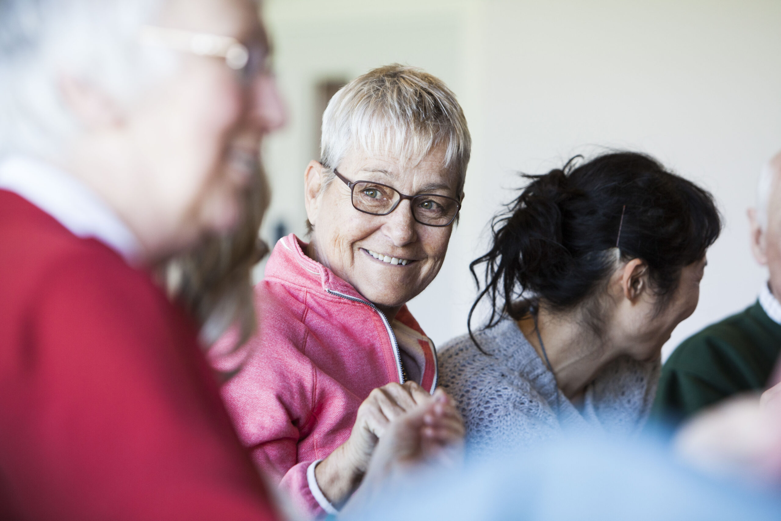 A group of people are sitting down, holding hands and smiling.